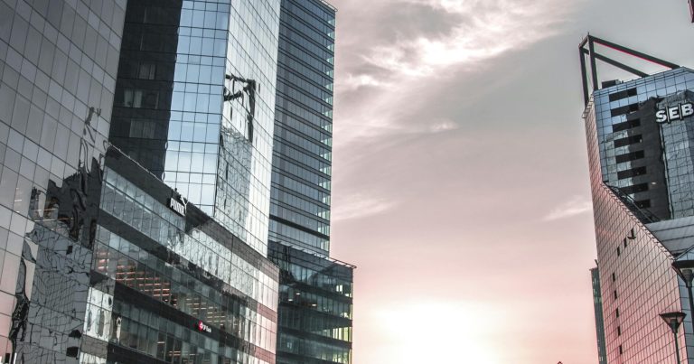 Urban cityscape of Tallinn with modern skyscrapers and sunset sky reflecting on buildings.